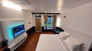 Habitación de hotel moderna con una cama grande, un televisor de pantalla plana en la pared y vistas al exterior mediante una puerta corrediza.