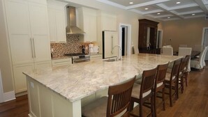 A spacious kitchen with a large island, white cabinetry, and a modern stove. - Luxury Construction With A Private Pool (Rehoboth Beach)