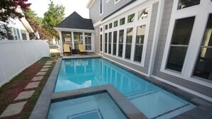 A rectangular swimming pool with a glass bottom, surrounded by a white fence and a small grassy area. - Luxury Construction With A Private Pool (Rehoboth Beach)