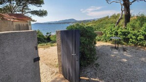 A rustic stone building with a gravel path leading to a wooden gate. - Apartment with a view of the garden and an unobstructed view of the ocean! (Le Pradet)
