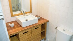 A bathroom with a white sink, wooden vanity, and a mirror. - Apartment with a view of the garden and an unobstructed view of the ocean! (Le Pradet)