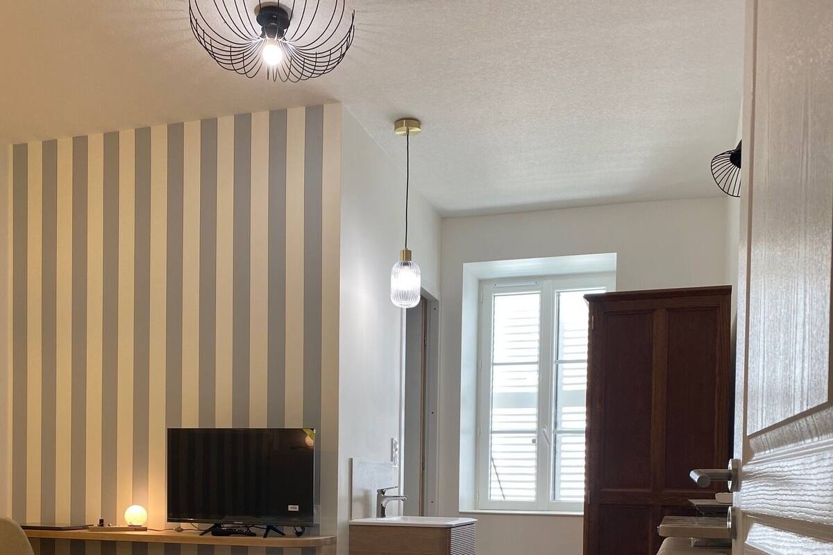 A bedroom with a bed, a TV, a radiator, and a window with blinds.
