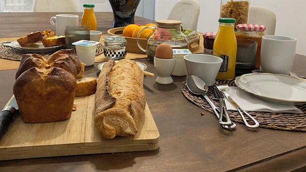 Una mesa de desayuno con pan, huevos y jugo de naranja.
