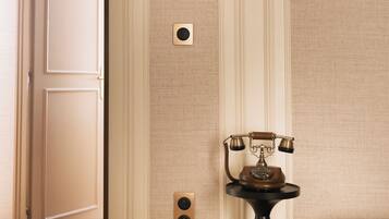 A room with a door, a wall-mounted telephone, and a small table with a telephone.