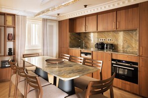 A modern kitchen with a marble countertop, wooden cabinets, and a built-in oven. - Merveil - Luxury Suite - Louvre - Rivoli (Paris)