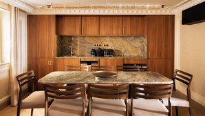 Una cocina moderna con armarios de madera, encimera de mármol y comedor con mesa y sillas de mármol.