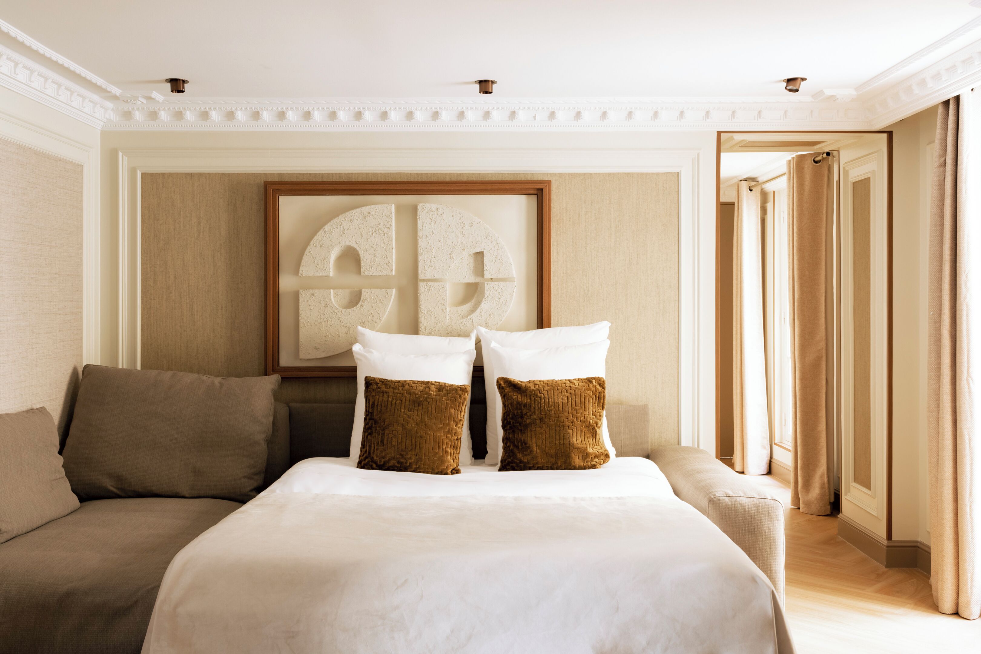 Ein Hotelzimmer mit einem großen Bett, zwei Kissen, einem Kopfteil und einem gerahmten Kunstwerk an der Wand.