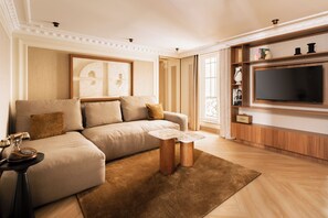 A modern living room with a sofa, coffee table, and a flat-screen TV mounted on the wall. - Merveil - Luxury Suite - Louvre - Rivoli (Paris)