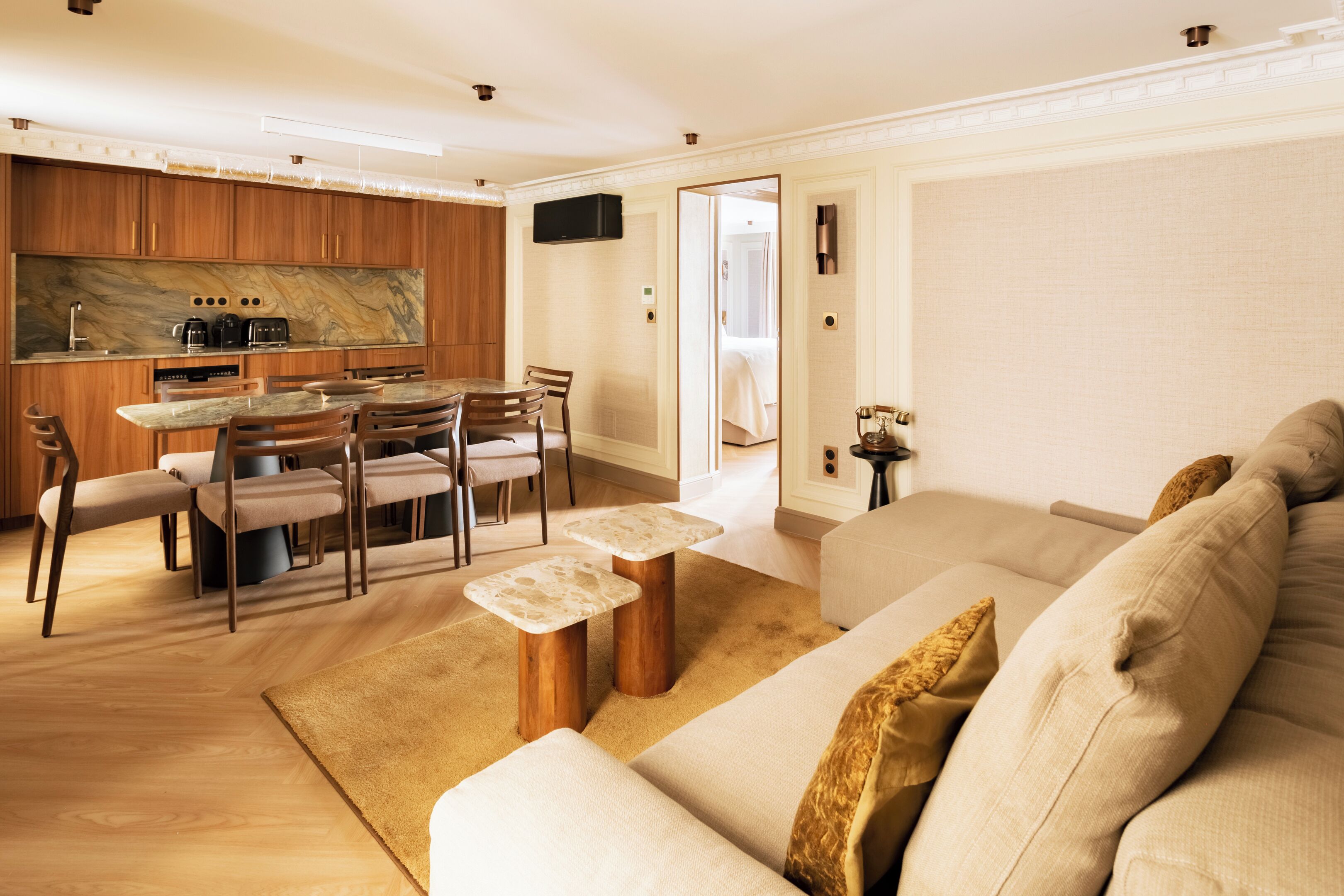 A modern living room with a sofa, a coffee table, and a dining area with chairs and a table.