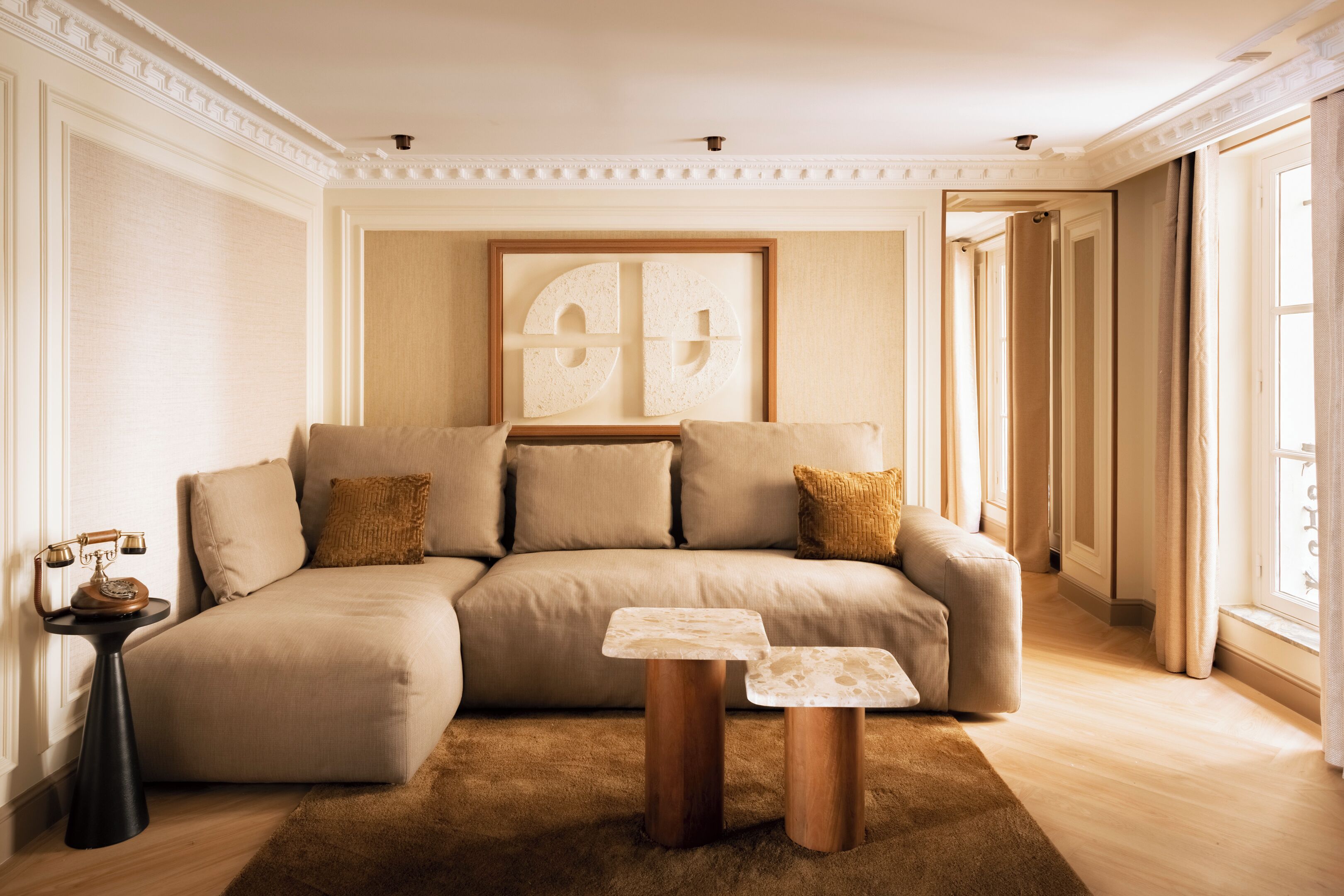 A living room with a sectional sofa, a small side table, and a framed artwork on the wall.