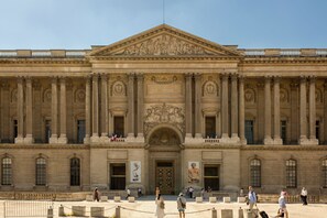 Un gran edificio de estilo clásico con una entrada central, flanqueada por columnas y esculturas detalladas.