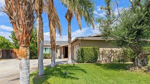A residential property with a well-maintained lawn, palm trees, and a garage. - Indio Poolside Retreat Getaway by Navigate Stays (Indio)