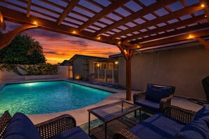 A pool area with a pergola, lounge chairs, and a small building with a balcony. - Indio Poolside Retreat Getaway by Navigate Stays (Indio)