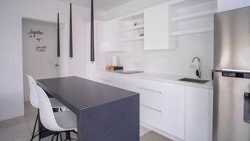 Eine moderne Küche mit weißen Schränken, einer dunklen Arbeitsplatte und einem Edelstahl-Kühlschrank.