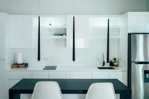 A modern kitchen with white cabinetry, a stainless steel refrigerator, and a black countertop. - Trankilidad 6 | Private Apt • Pool • Central Aruba (Santa Cruz)