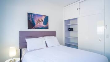 Een slaapkamer met een bed, een nachtkastje, een lamp, een schilderij en een garderobe.