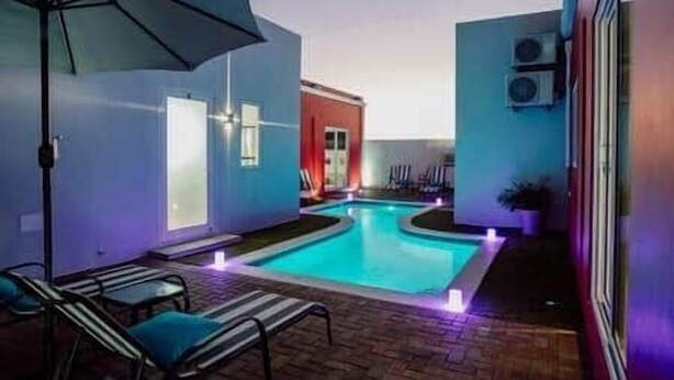 Un espace piscine avec des chaises longues et un parasol.