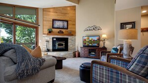 A cozy living room with a fireplace, comfortable seating, and a television. - RA410 | Excellent Amenities | Winter Shuttle | Pool | Hot Tub | Views (Steamboat Springs)