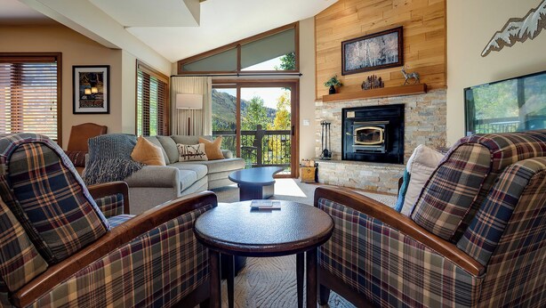 A cozy living room with plaid furniture, a fireplace, and a scenic view. - RA410 | Excellent Amenities | Winter Shuttle | Pool | Hot Tub | Views (Steamboat Springs)