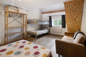 Ein Schlafsaalzimmer mit Etagenbetten, einem Schreibtisch, einem Stuhl und einem Fenster mit Vorhängen.