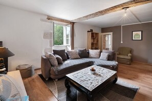 Una sala de estar con un sofá modular, una mesa de centro, una estantería y un sillón.