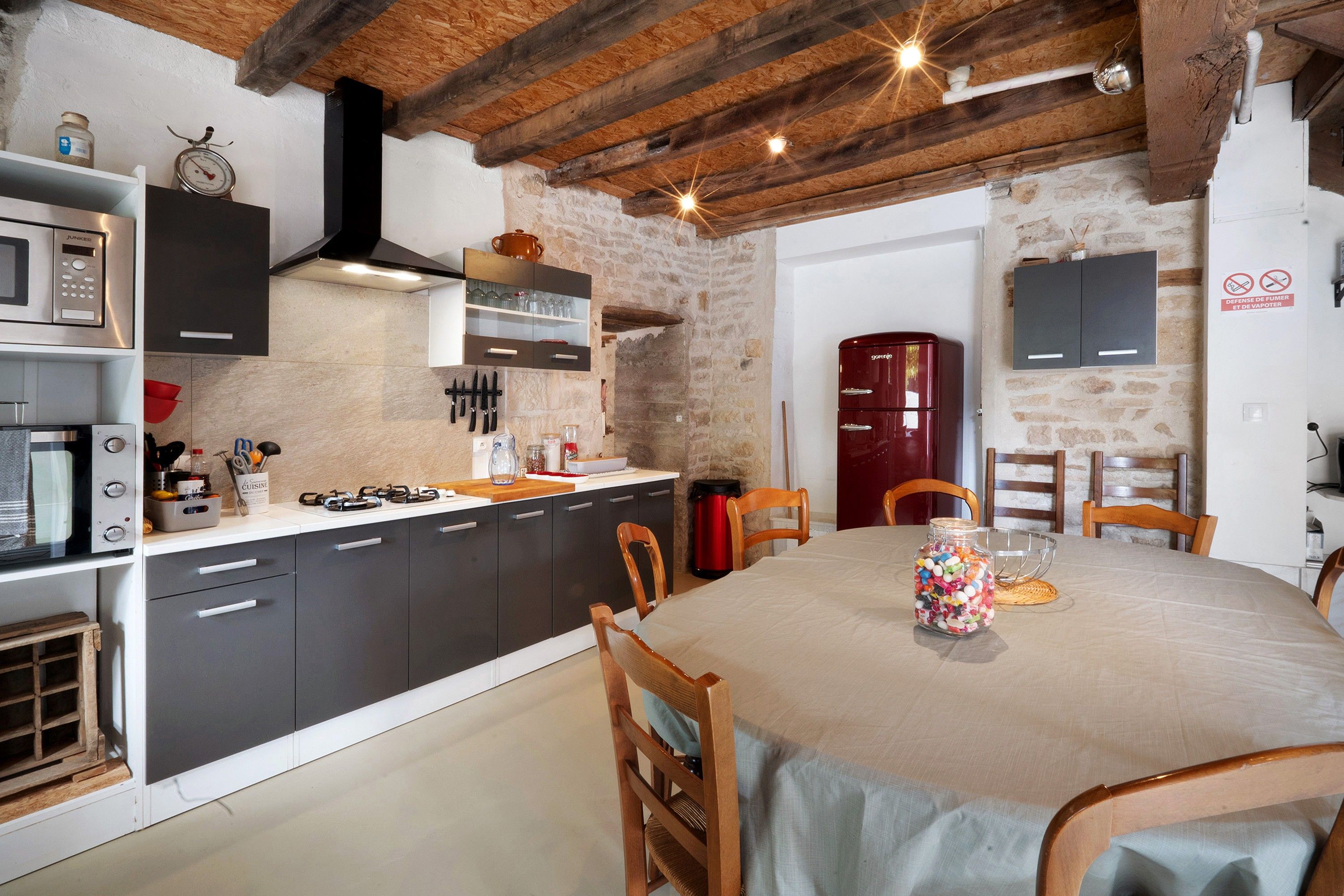 Une cuisine équipée d’appareils électroménagers modernes, une table à manger avec des chaises et un mur en pierre.