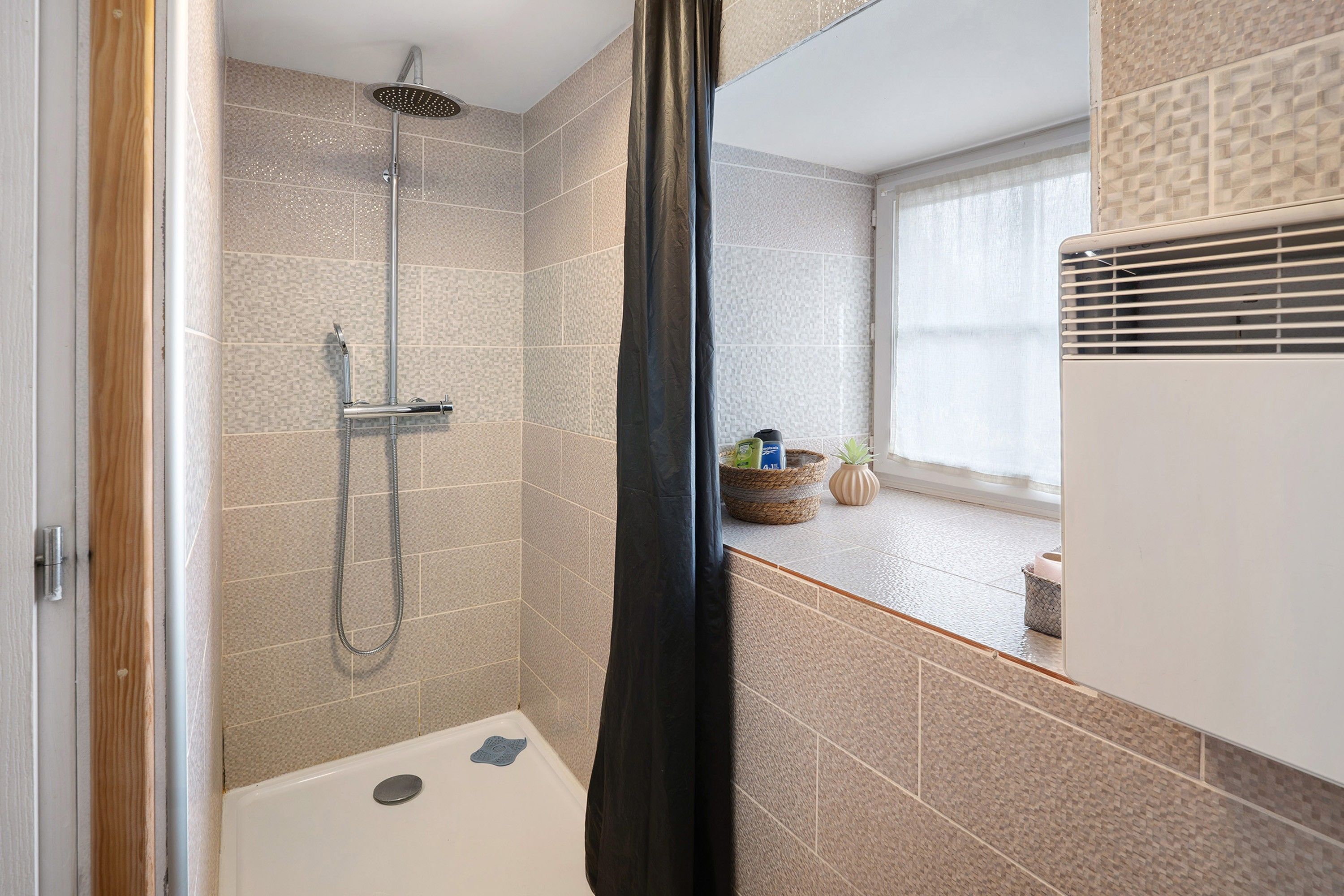 A bathroom with a shower, a bathtub, and a window with a view.