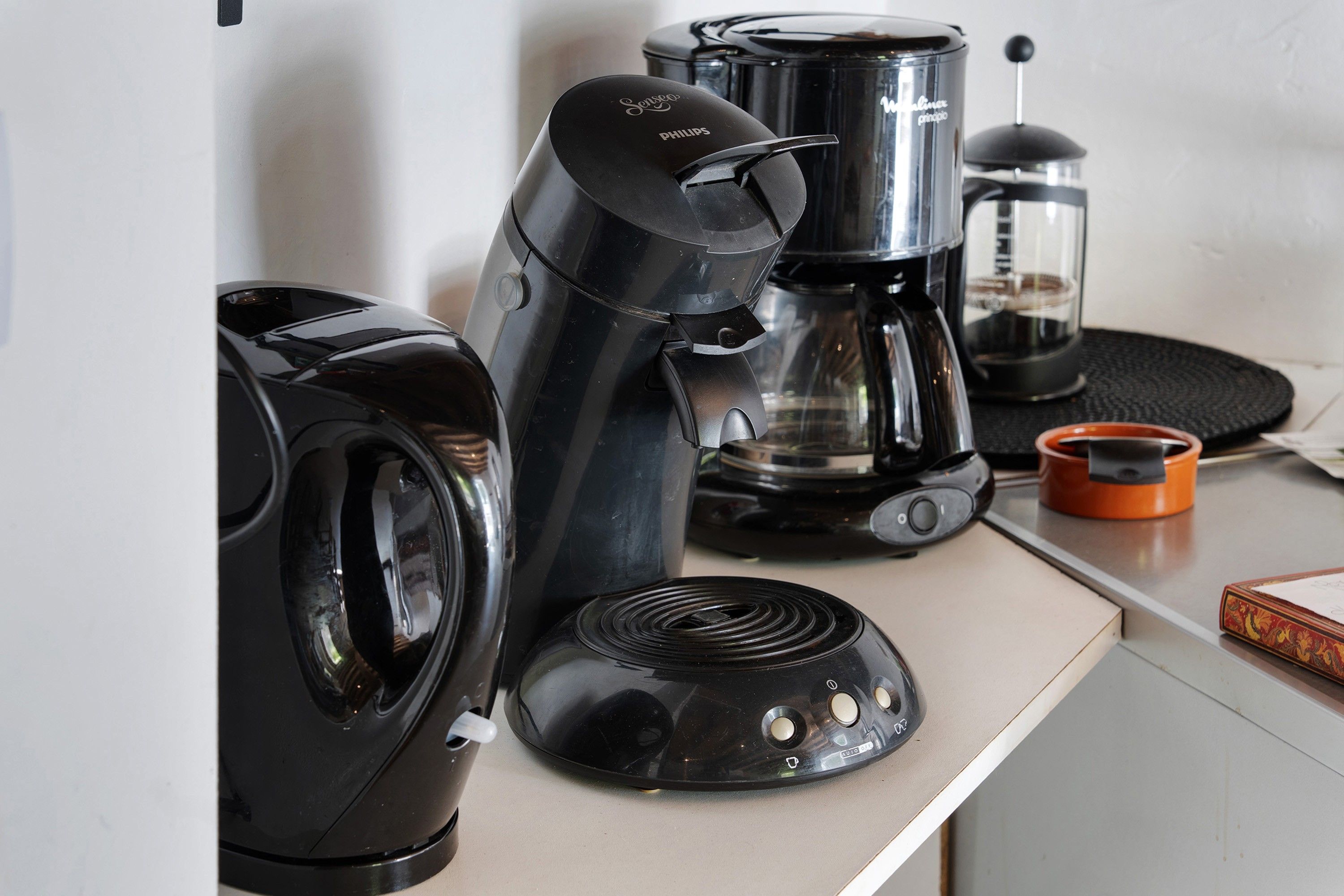 A kitchen counter with a coffee maker, a blender, and a kettle.