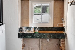 Una cocina con encimera de mármol, una ventana con vistas y un lavabo con grifo.