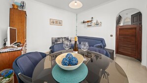 Un comedor con una mesa, sillas, un cuenco de bolas decorativas, una botella y copas de vino.