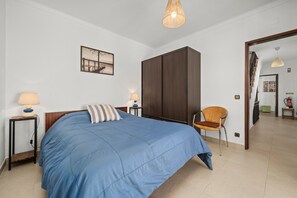A bedroom with a bed, a chair, a wardrobe, a lamp, and a painting on the wall. - Casa Tété in Benagil – Authentic Algarve Charm Steps from the Beach (benagil)