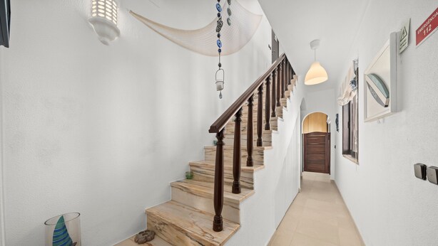 Una escalera con peldaños de mármol y barandillas de madera, que conduce a un rellano con una puerta de madera.
