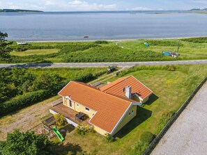 A house with a red-tiled roof, a fenced yard, and a view of a body of water. - 5 Star Holiday Home in Knebel (Knebel)