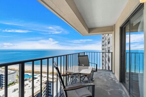 A balcony with a view of the ocean, two chairs, and a glass door. - Myrtle Beach Resort RT1717 (Myrtle Beach)
