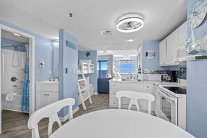 Une cuisine moderne avec des meubles blancs, une table à manger et une vue sur la mer.