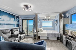 A modern room with a balcony, a bed, a sofa, and a TV.