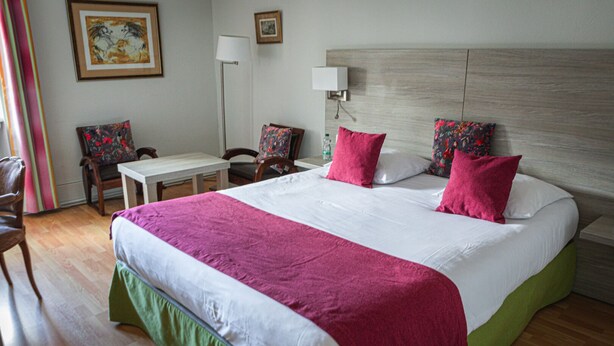 A hotel room with a large bed, a desk, two chairs, and a nightstand. - Hotel de la Poste - Benjamin Linard  (Pouilly-en-Auxois)