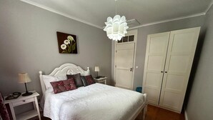 Un dormitorio con cama, mesitas de noche, lámpara, un cuadro y armario.