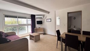 A modern living room with a sofa, a coffee table, a TV, and a dining area with chairs and a table. - Apartment in Vernet-les-bains With Pool (Vernet-les-Bains)