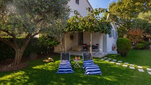 A house with a covered patio, two lounge chairs, and a small table with drinks.