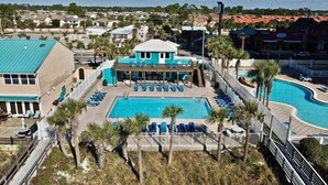 Un complexe hôtelier doté d’une grande piscine, d’un bâtiment séparé avec un toit bleu et offrant une vue sur les environs.