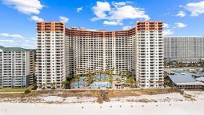 A high-rise hotel with a curved facade, multiple balconies, and a central pool area. - Lagoon Lookout 811-Gulf-Front Views-Sleeps 6 (Panama City Beach)