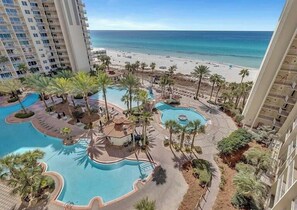 Ein Resort mit mehreren Schwimmbecken, Palmen und Blick auf den Strand.