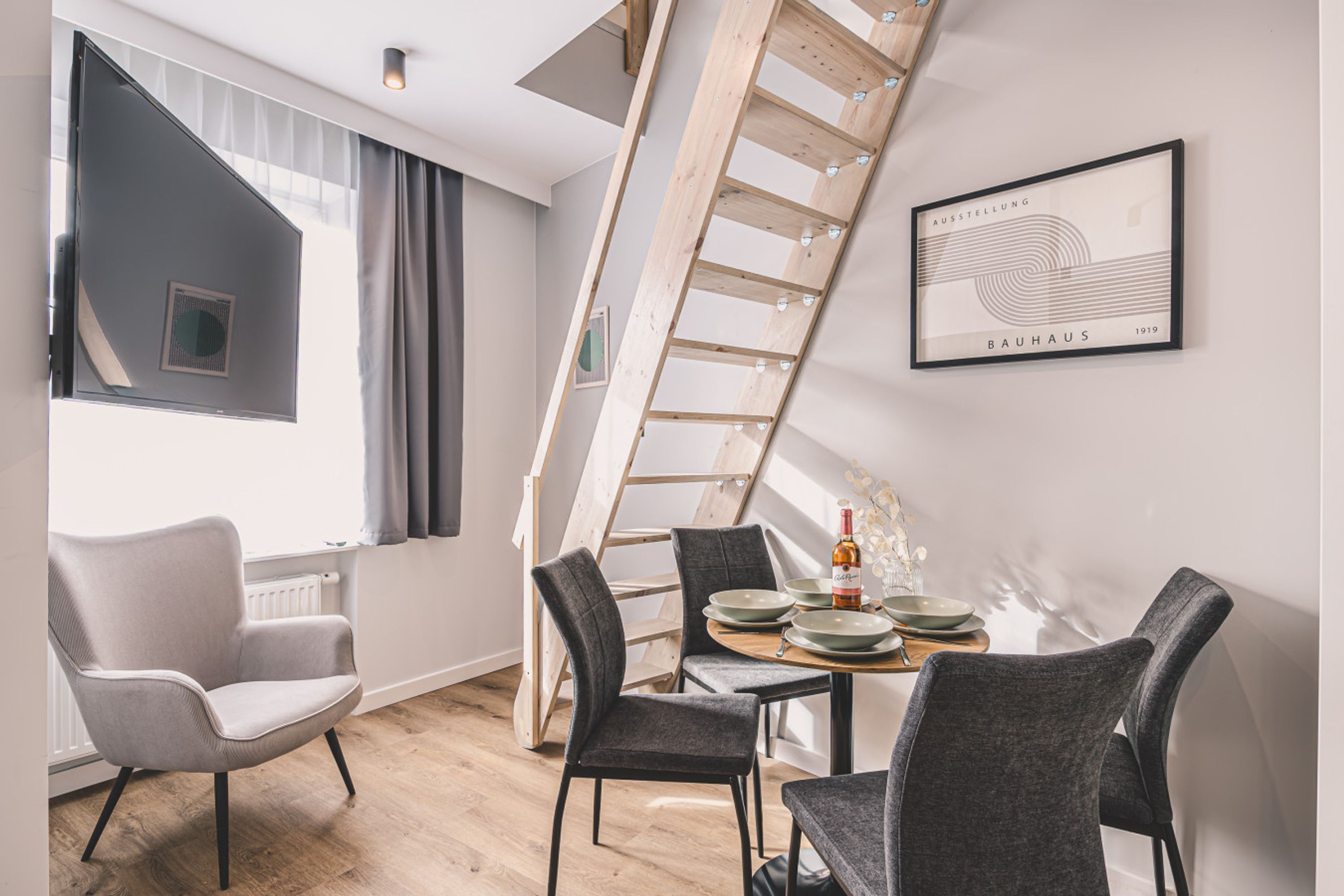Ein modernes Interieur mit Essbereich, Treppe und einem gerahmten Kunstwerk an der Wand.