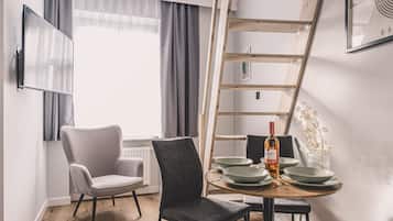 Un espace repas moderne avec une échelle en bois, deux chaises, une table dressée avec des assiettes et une bouteille, et une fenêtre avec des rideaux.
