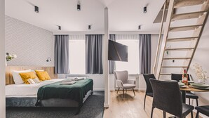Een moderne hotelkamer met een bed, een bureau met een stoel, een televisie en een houten trap.