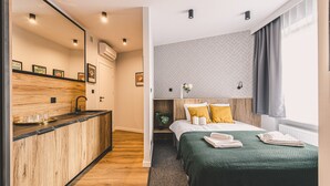 Een hotelkamer met een houten bar, een bed met groene beddengoed en een raam met gordijnen.
