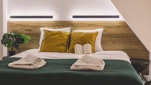 Una cama bien hecha con una manta verde, dos almohadas y un libro.