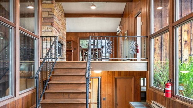 Interior de madera con una escalera, ventanas amplias y un extintor.