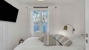 A bedroom with a bed, a TV mounted on the wall, a window with curtains, and a bedside lamp. - 5 Star Holiday Home in Hillerod (Hillerod)